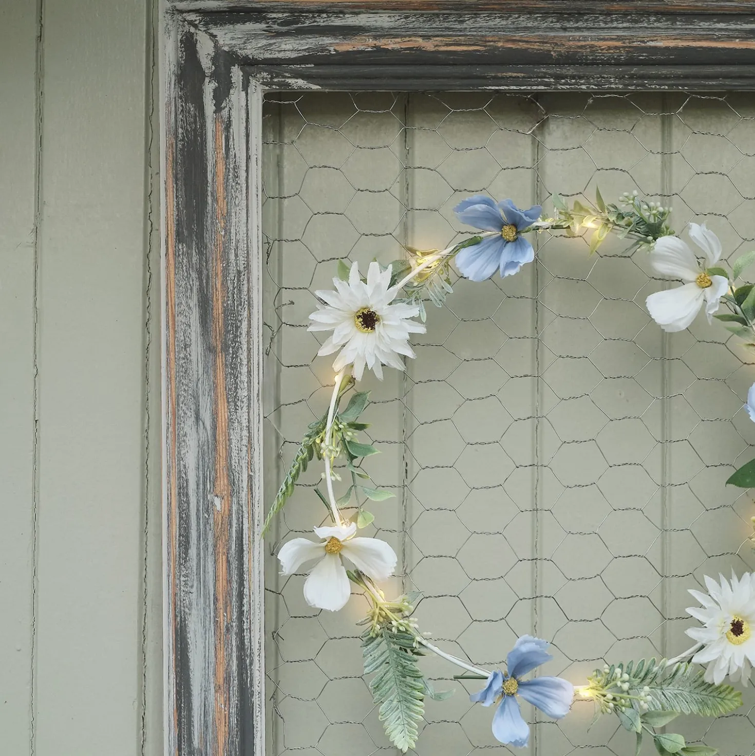 Beleuchteter Kranz und Girlande mit blauen und weißen Blüten